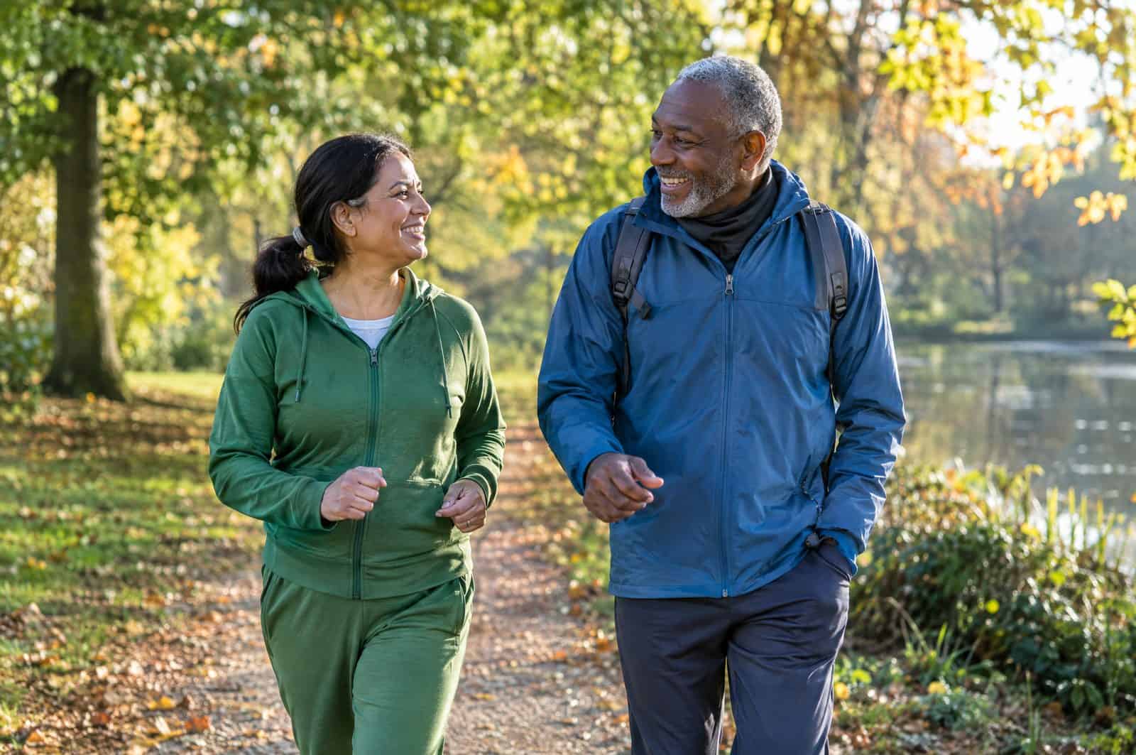 Two friends walking briskly and chatting on a leafy park path on a bright autumn morning